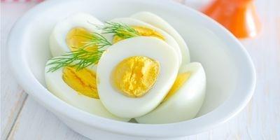 把煮熟的鸡蛋切成两半，放在白色的碗里，用新鲜的莳萝装饰.